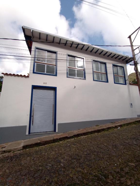 a white house with a blue door at Casa nova com suítes amplas in Ouro Preto