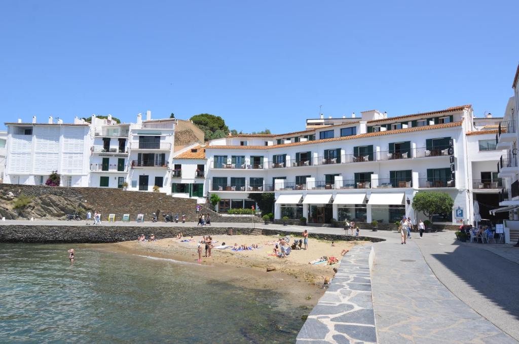 a group of people on a beach next to a building at Hotel Playa Sol in Cadaqués