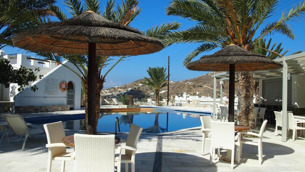 a patio with chairs and umbrellas next to a pool at Homer's Inn Hotel in Ios Chora