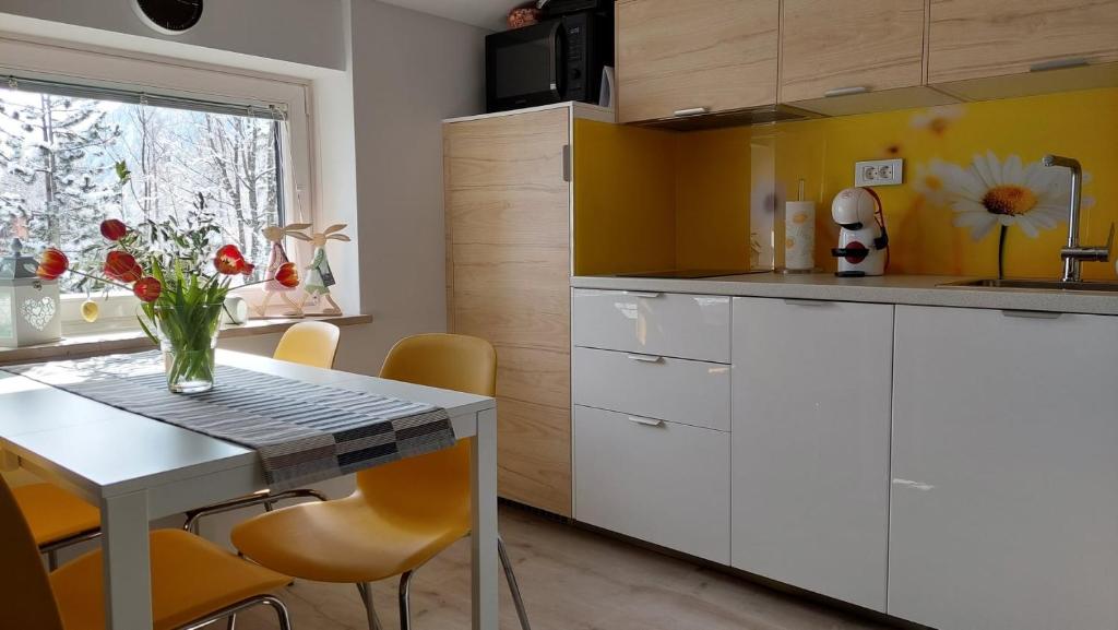 a kitchen with white cabinets and a table with a vase of flowers at Apartma Marjetica in Gozd Martuljek
