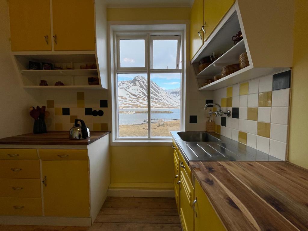 eine gelbe Küche mit einem Waschbecken und einem Fenster in der Unterkunft The Old Bookstore in Flateyri