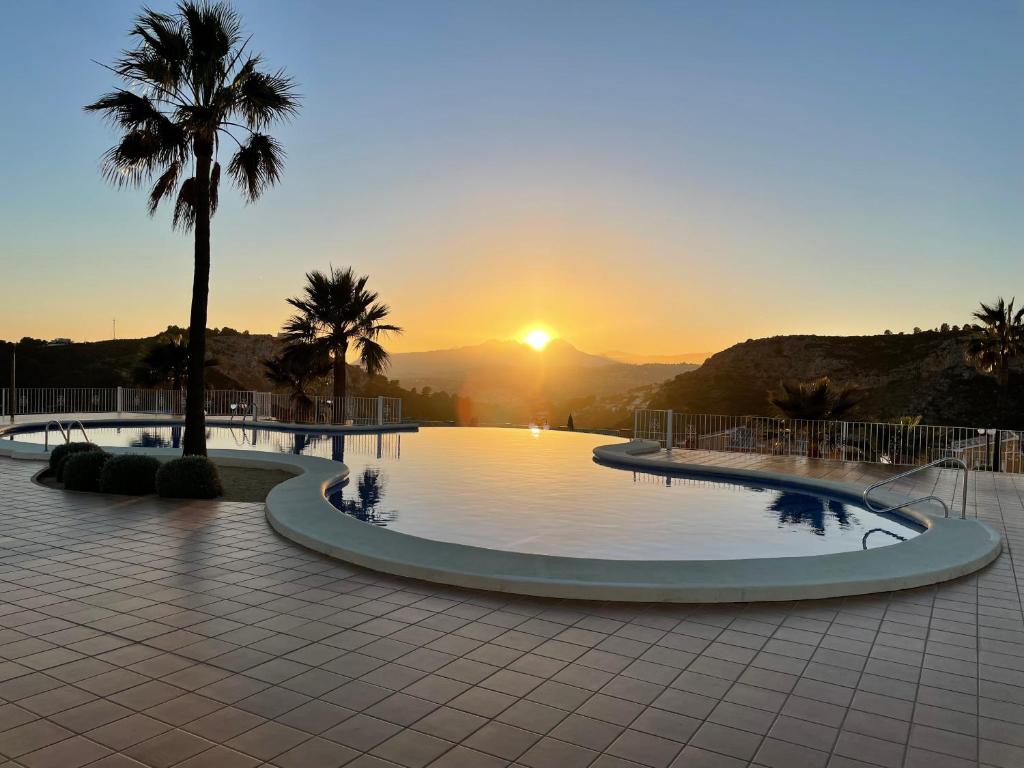 una gran piscina con puesta de sol en el fondo en Tranquility, sun, breathtaking views & 7 minutes drive to sea, en Benitachell