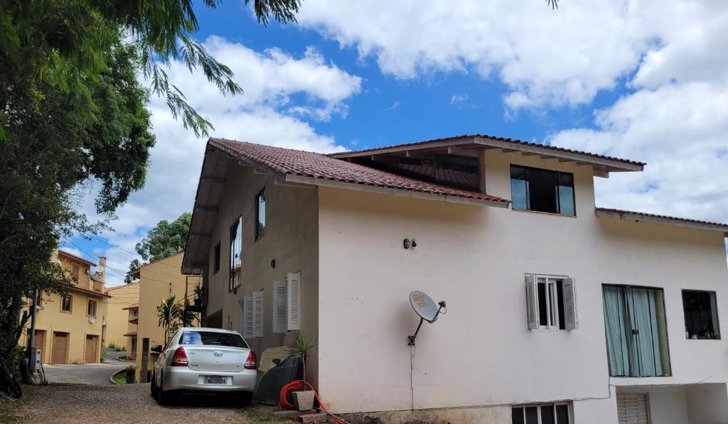 um carro estacionado em frente a uma casa branca em lugar tranquilo aconchegante perto da natureza em Nova Petrópolis