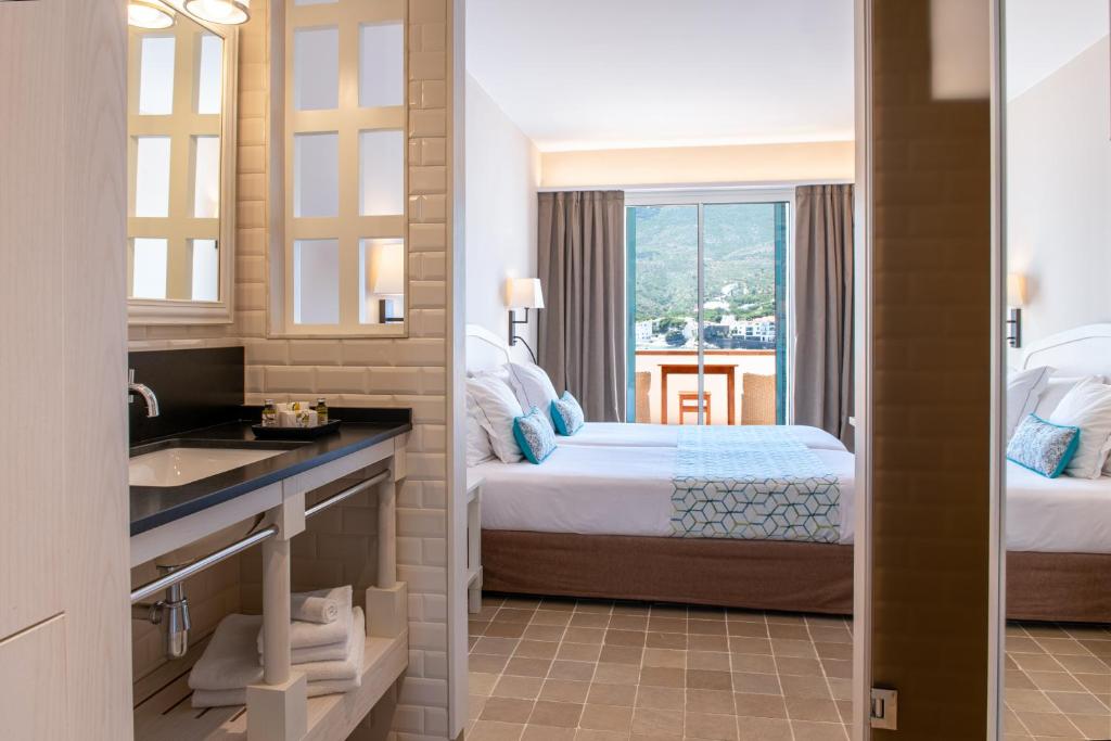 a bathroom with a bed and a sink in a room at Hotel Playa Sol in Cadaqués