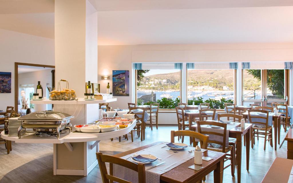 a restaurant with tables and chairs and windows at Hotel Playa Sol in Cadaqués
