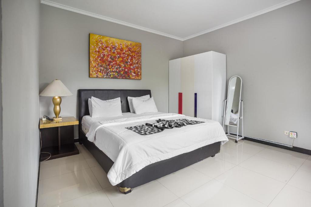 1 dormitorio con 1 cama y una pintura en la pared en Villa Alessa Puncak en Puncak