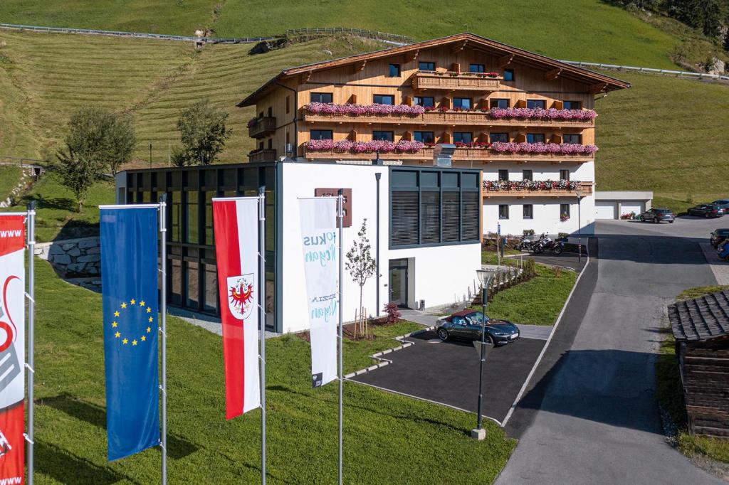 un bâtiment avec drapeaux devant lui dans l'établissement Hotel FoKus, à Sankt Jakob in Defereggen