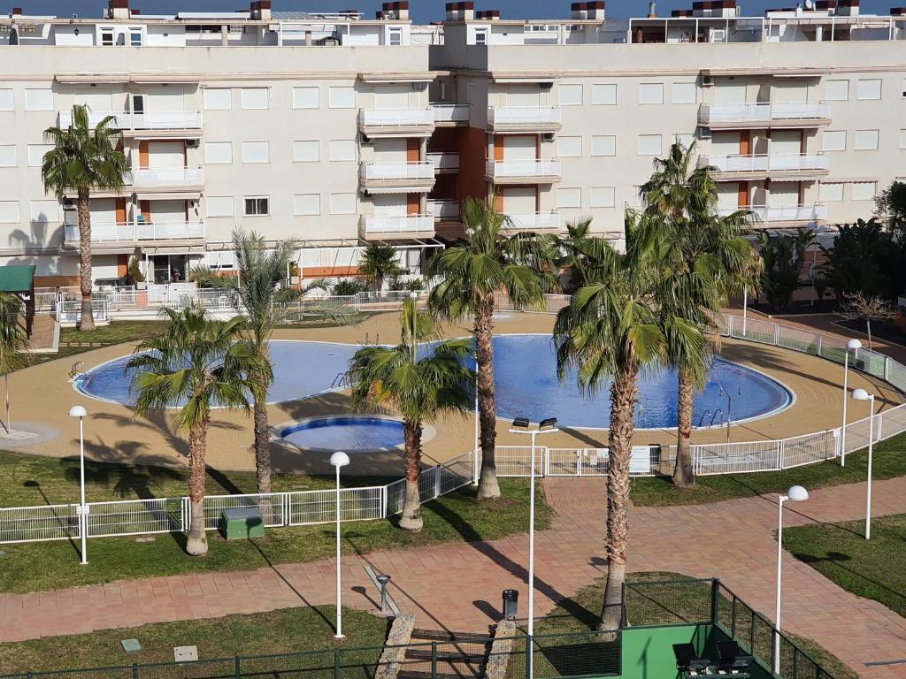 a building with palm trees and a swimming pool at Apartamento Almenara Nova Almenareta in Almenara