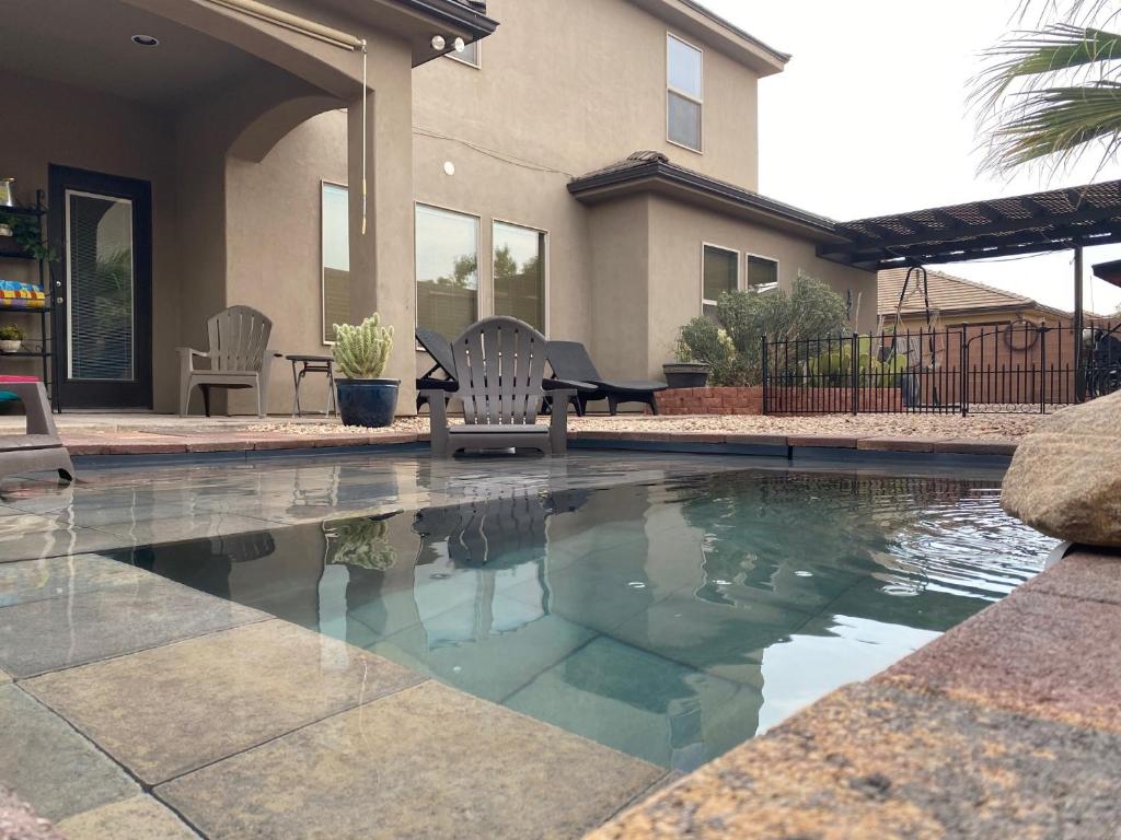 a swimming pool with two chairs and a house at Tiny RV Stone pool Inn, Pets stay free, Zion National Park, your private Oasis! in St. George