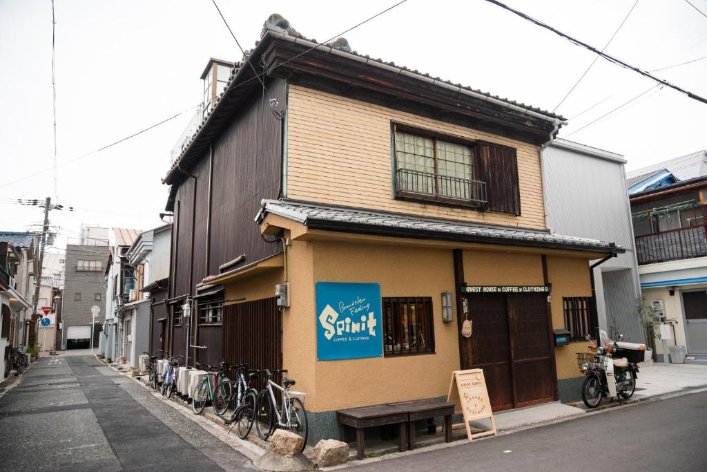 ゲストハウス君彩家 kimidoriya في أوساكا: مبنى صغير مع دراجات متوقفة خارجه