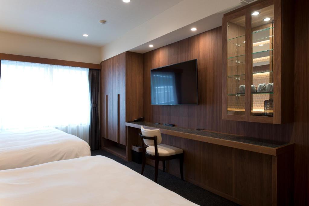 a hotel room with a bed and a tv at Kadoya Hotel in Tokyo