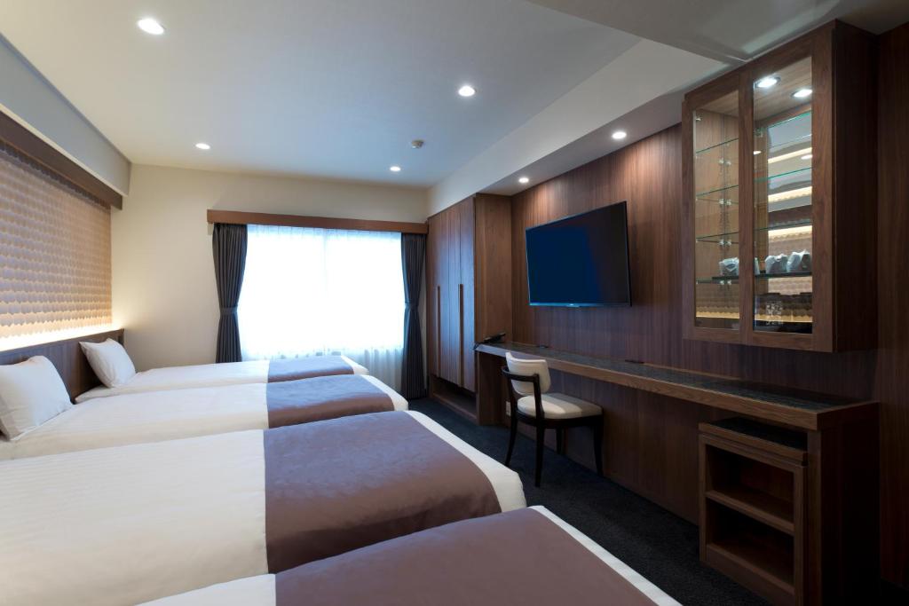 a hotel room with two beds and a television at Kadoya Hotel in Tokyo