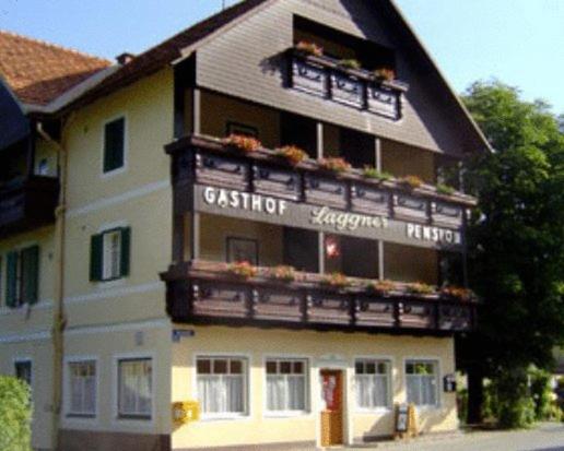 ein großes Gebäude mit einem Balkon mit Blumen darauf in der Unterkunft Gasthof Laggner in Steindorf am Ossiacher See
