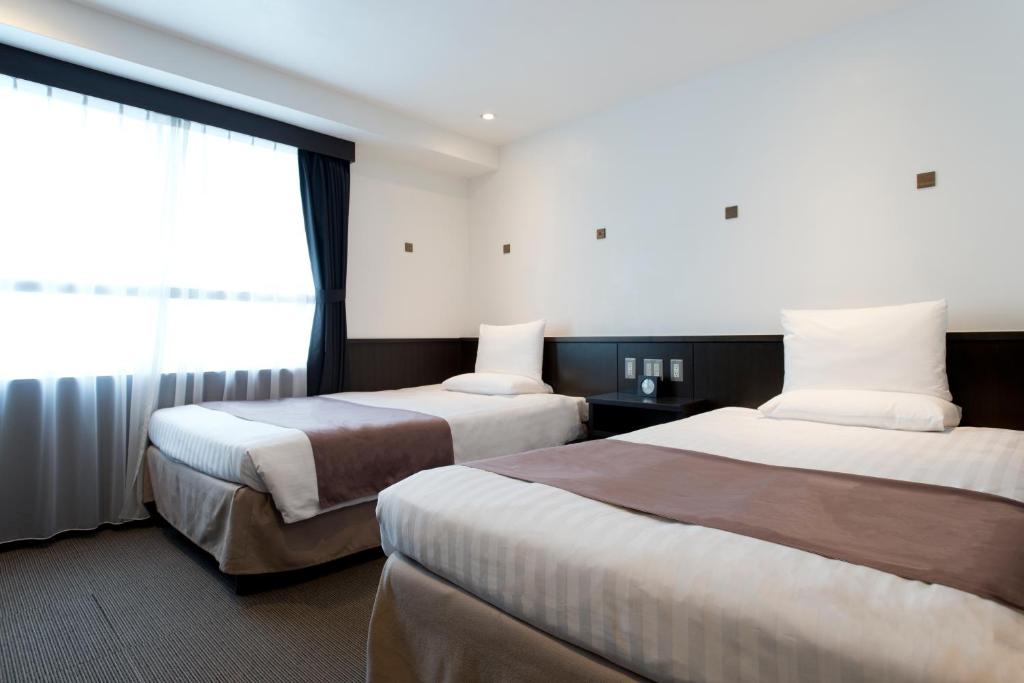 a hotel room with two beds and a window at Kadoya Hotel in Tokyo