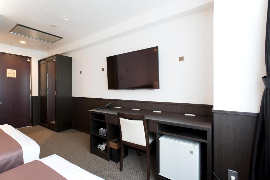 a hotel room with a desk and a flat screen tv at Kadoya Hotel in Tokyo