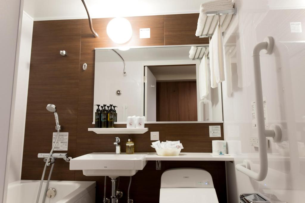 a bathroom with a sink and a toilet and a mirror at Kadoya Hotel in Tokyo