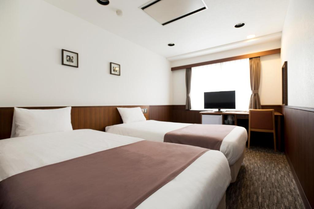 a hotel room with two beds and a television at Kadoya Hotel in Tokyo