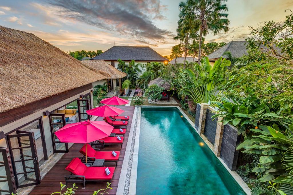 an image of a resort pool with red chairs and umbrellas at The Residence Seminyak in Seminyak
