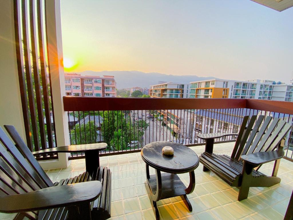 a balcony with two chairs and a table with a view at The Empire Nimman in Chiang Mai