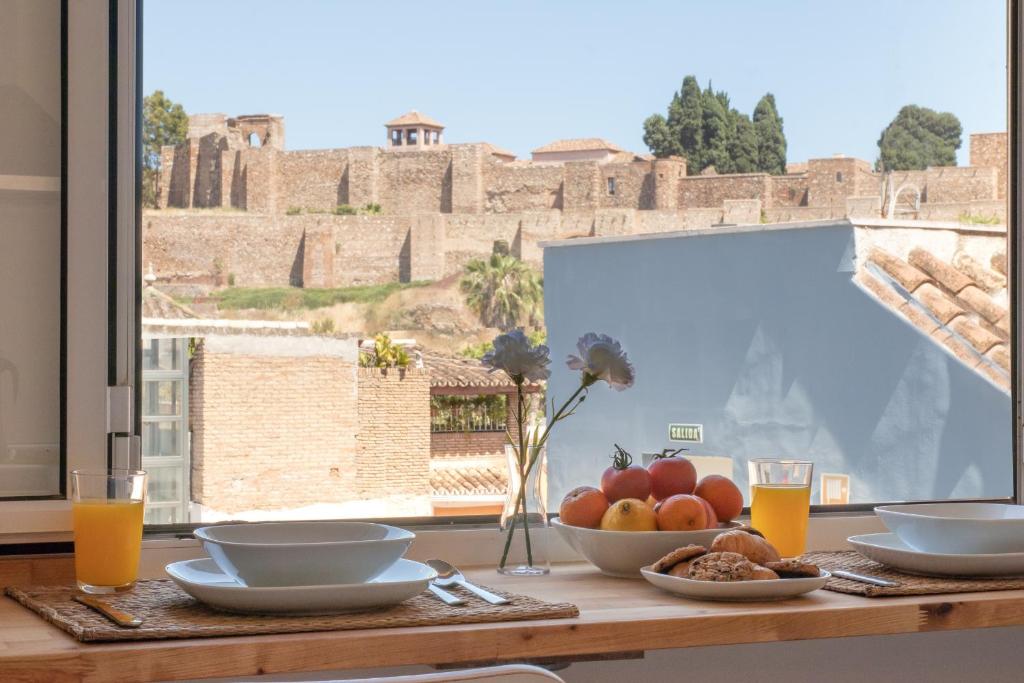 una mesa con un bol de fruta y vasos de zumo de naranja en C79 - Fabulous Apartment Alcazaba Views, en Málaga