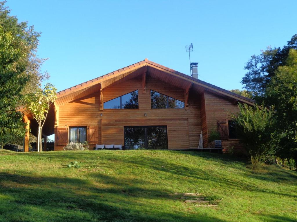 a large wooden house on a green lawn at Le Barail 31 in Couret