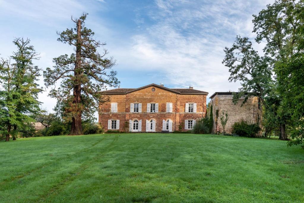 an old brick house with a large grassy yard at Appartements au Château Ars in Ars-sur-Formans