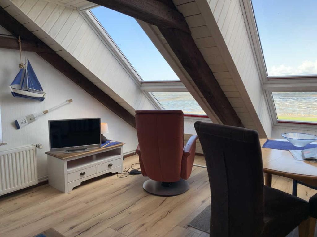 a attic room with a television and a desk with a chair at Ferienwohnung Frische Brise in Nordstrand