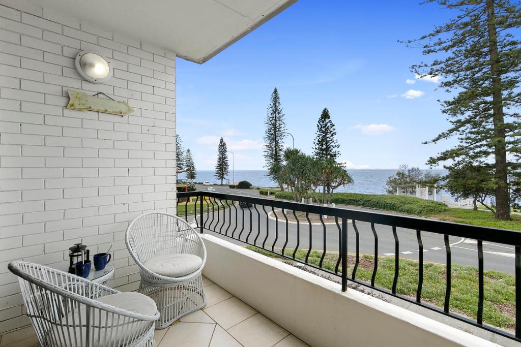 a balcony with two chairs and a view of the ocean at Beachwood at Margate Beach in Redcliffe