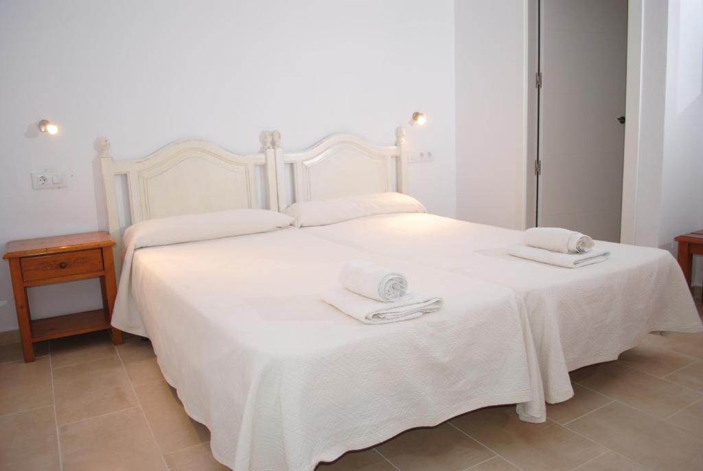 Una cama blanca con dos toallas encima. en Hostal Paris Ciutadella, en Ciutadella