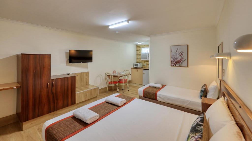 ローマにあるBryants Motel Romaのベッド2台とテレビが備わるホテルルームです。