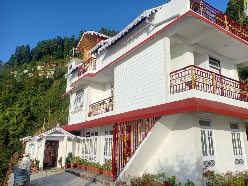 uma casa branca com varandas vermelhas numa montanha em Hermit Retreat em Darjeeling