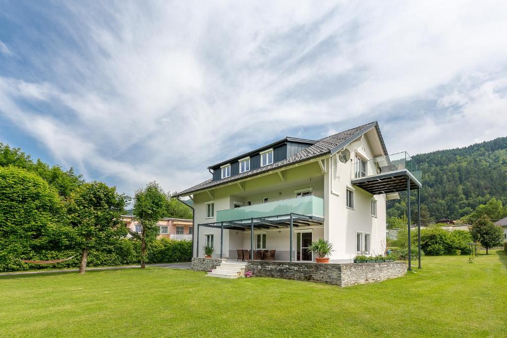 ein Haus mit grünem Rasen davor in der Unterkunft Villa Müller Turmfalke in Ossiach