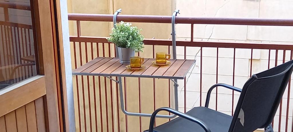 a table with two cups and a plant on a balcony at Appartamento Vittoria in Trapani