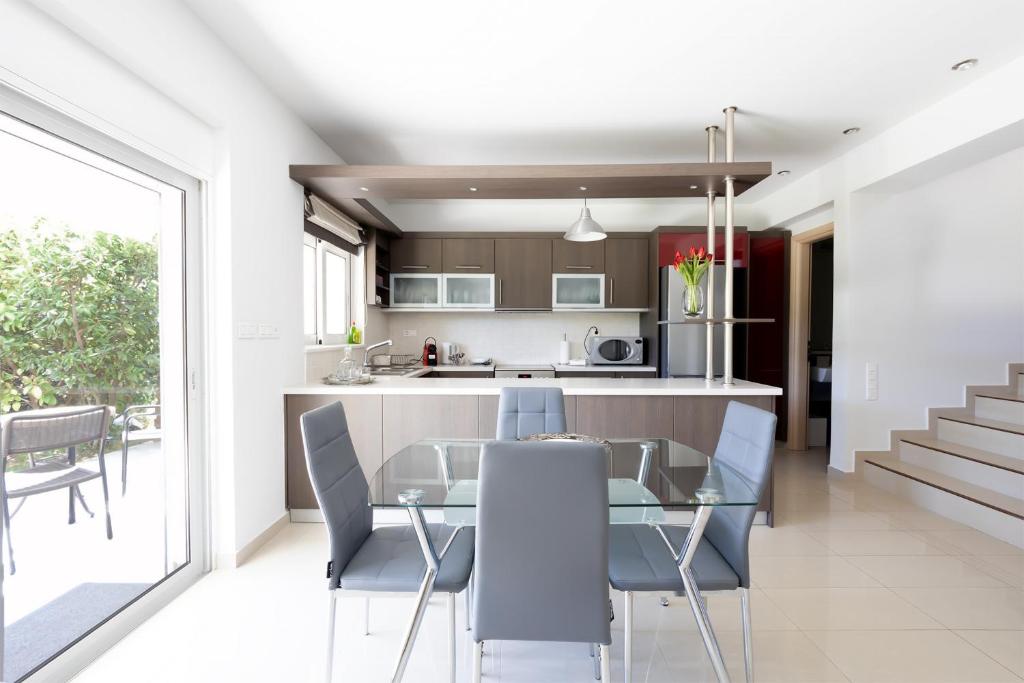 uma cozinha e sala de jantar com uma mesa de vidro e cadeiras em Athenian Riviera Maisonette, Varkiza, 7min walk from Beach Park em Vári