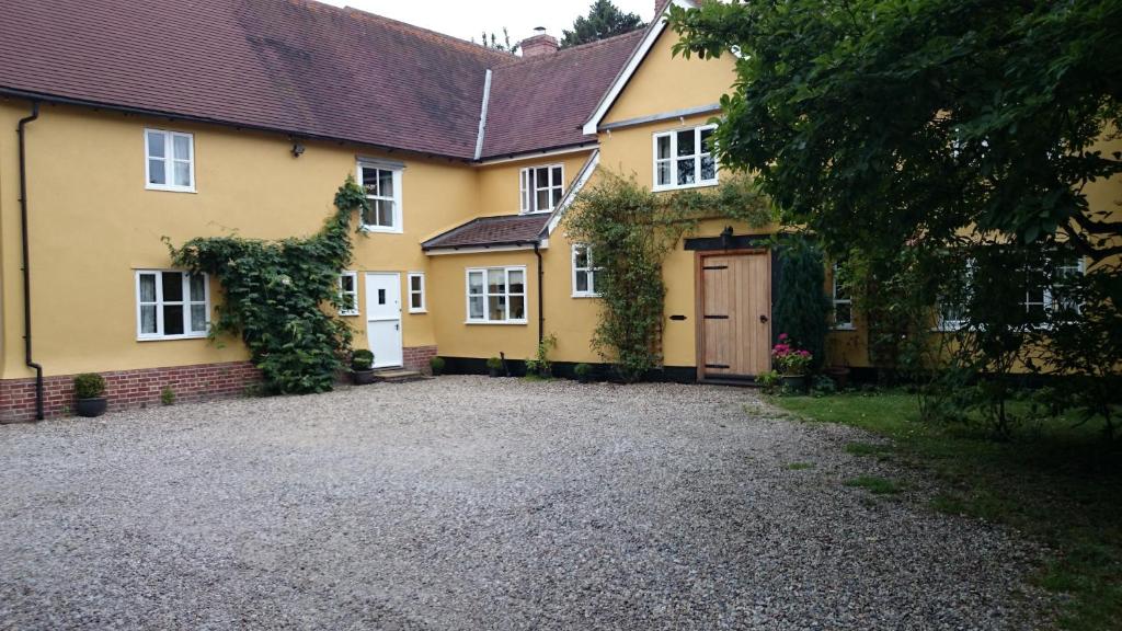 a yellow house with a driveway in front of it at The Martins B&B in Chelsworth