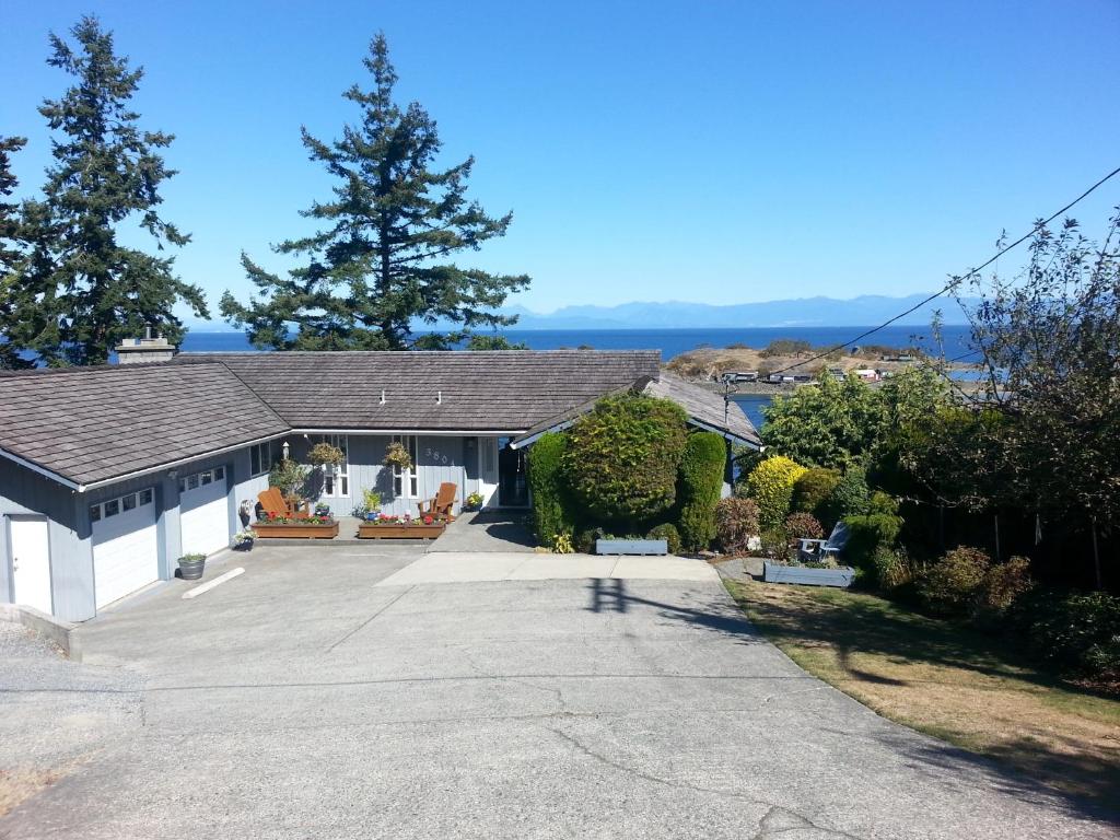 a house with a large driveway in front of it at Hammond Bay Oceanside Guesthouse in Nanaimo