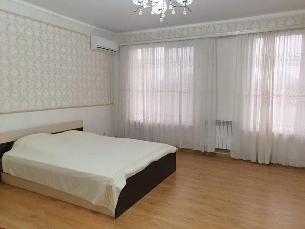 a bedroom with a bed and curtains and a chandelier at БЕЛЫЙ ДОМ in Gudauta