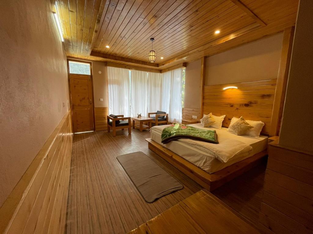 1 dormitorio con 1 cama grande y techo de madera en Hidab Homes, en Jibhi