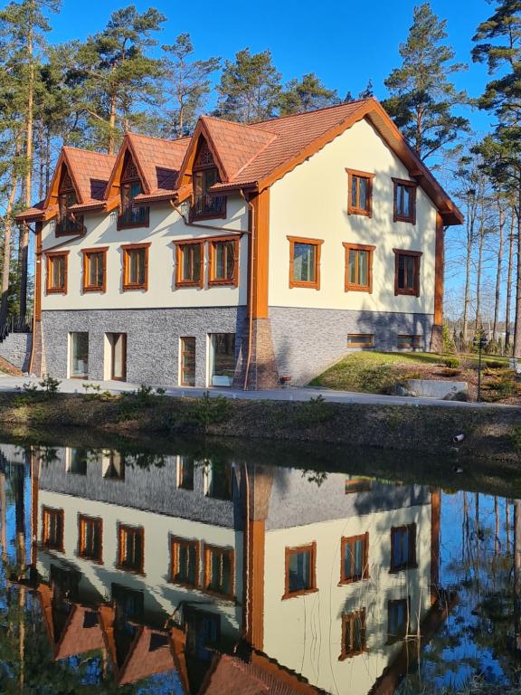 een huis met zijn reflectie in het water bij Grundenberga in Baldone