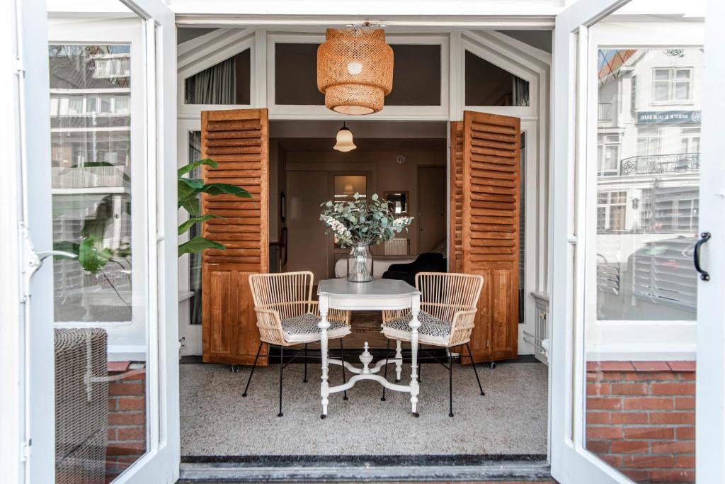 a porch with a white table and chairs and a window at Studio Loren / Studio Fellini in Zandvoort