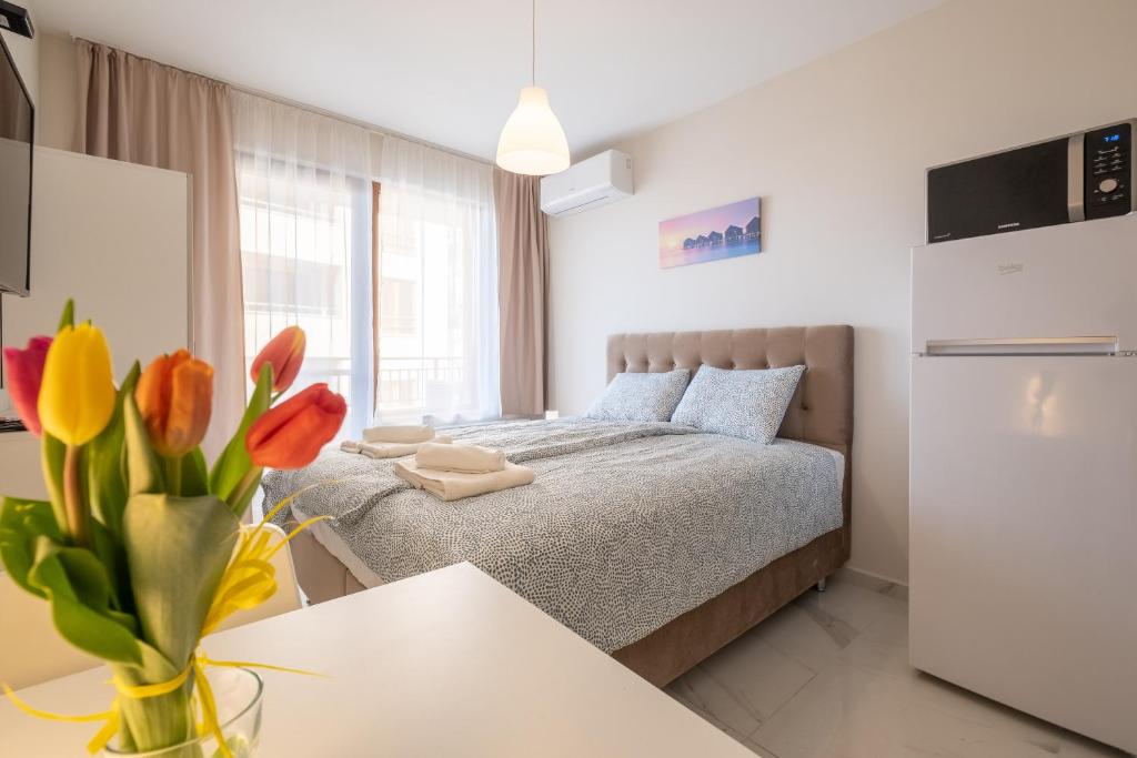 Sunny Dream Apartments في صوفيا: غرفة نوم مع سرير مع إناء من الزهور