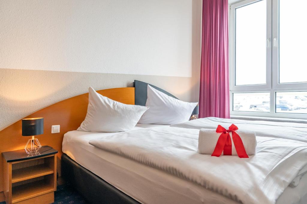 a hotel room with a bed with a bow on it at Hotel Belmondo Leipzig Airport in Wiedemar