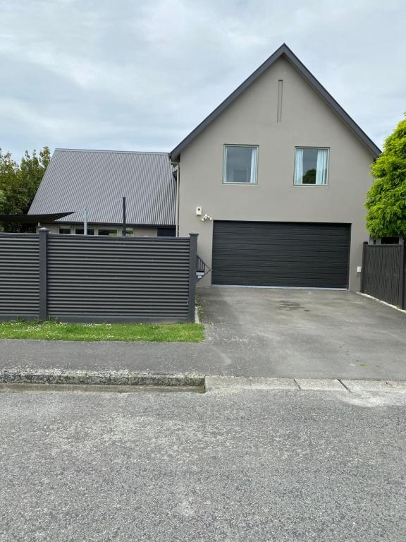una casa blanca con una valla y un garaje en Home By Hagley Park en Christchurch