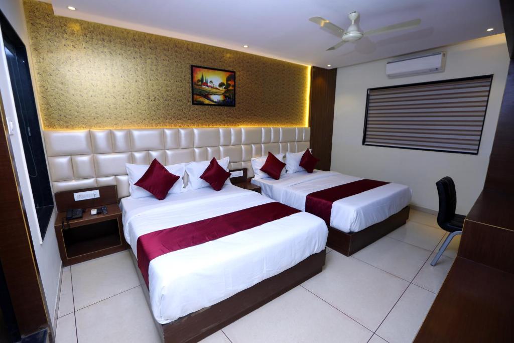 una camera d'albergo con due letti con cuscini rossi di Hotel Hindustan Residency Thane a Thane