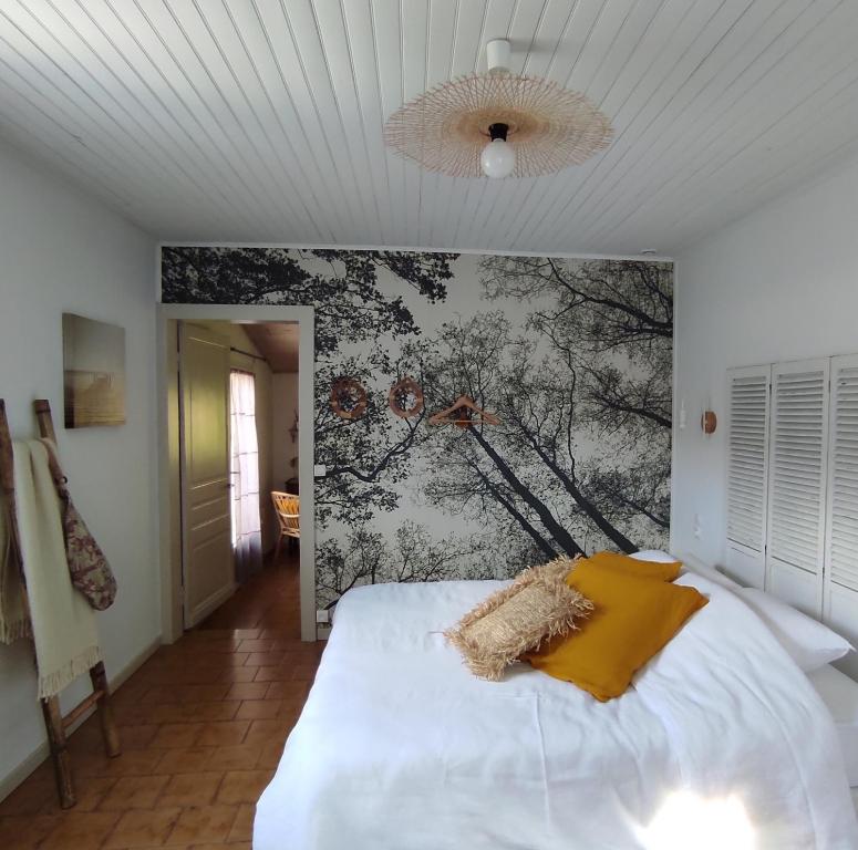 um quarto com uma cama branca e uma pintura na parede em Les jardins de Mimizan em Mimizan