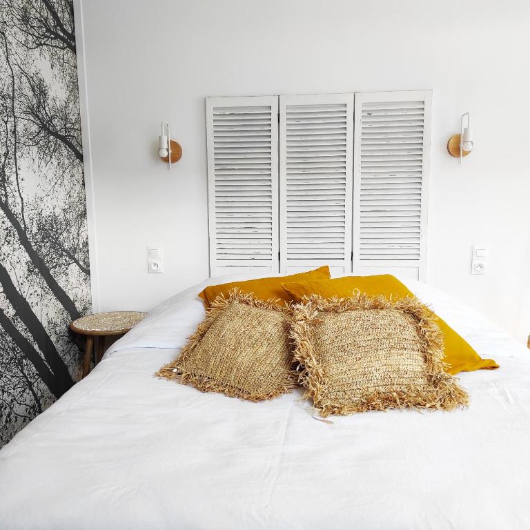 - un lit blanc avec un oreiller jaune dans l'établissement Les jardins de Mimizan, à Mimizan