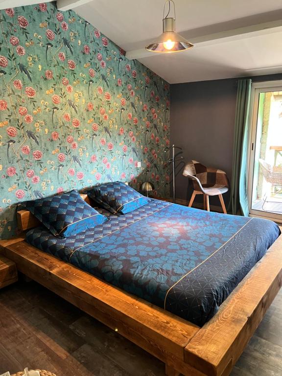 a bed in a bedroom with a floral wall at Relais de la Venise verte in Coulon