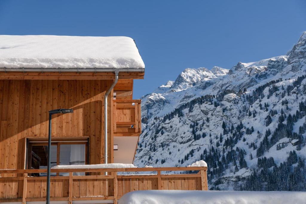 una cabaña de madera en las montañas con nieve en el techo en Le Refuge des Sens chalet Sérénité, en Vaujany