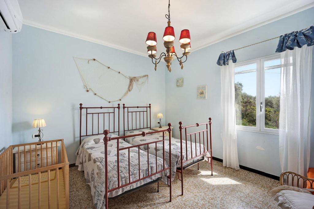 a bedroom with two beds and a chandelier at Appartamento La Buraggia in Diano San Pietro