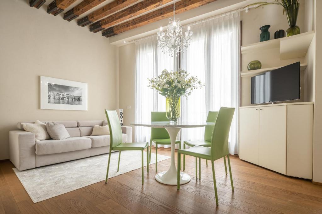 a living room with a table and green chairs at Santa Fosca Design Apartment R&R in Venice